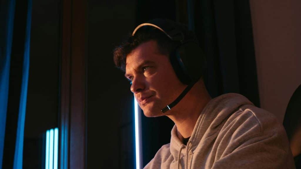 A man wearing a gaming headset, focused while sitting indoors.