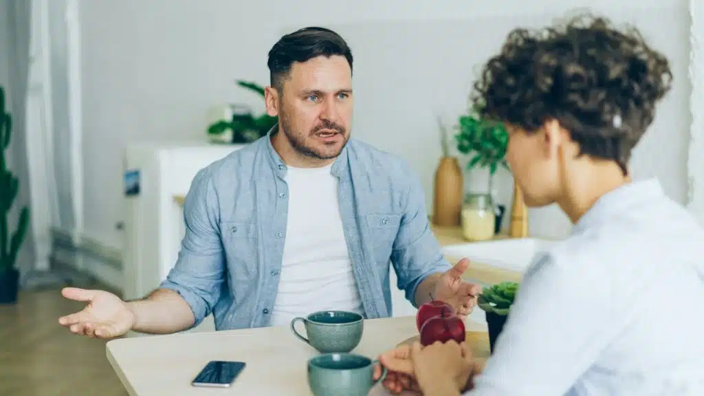 A man talking to a woman at a table.