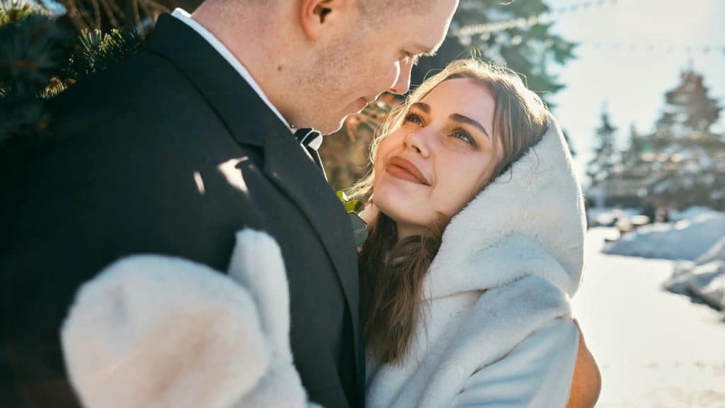 A couple looking lovingly at each other outdoors in winter clothing.