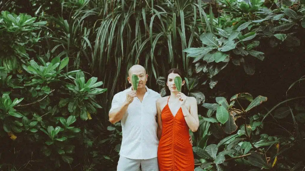 A man and woman standing in front of a forest.