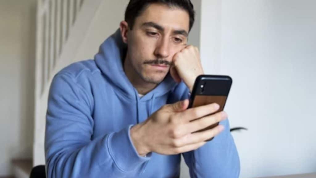 Man scrolling on phone looking discouraged