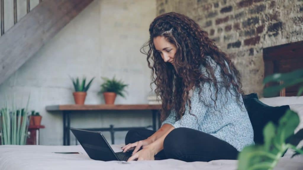 Woman closing her laptop while smiling, signaling the end of her workday