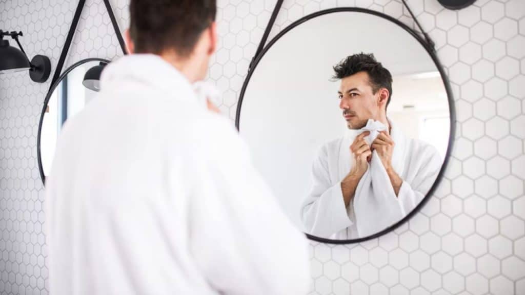 Man staring at his reflection in the mirror, looking contemplative