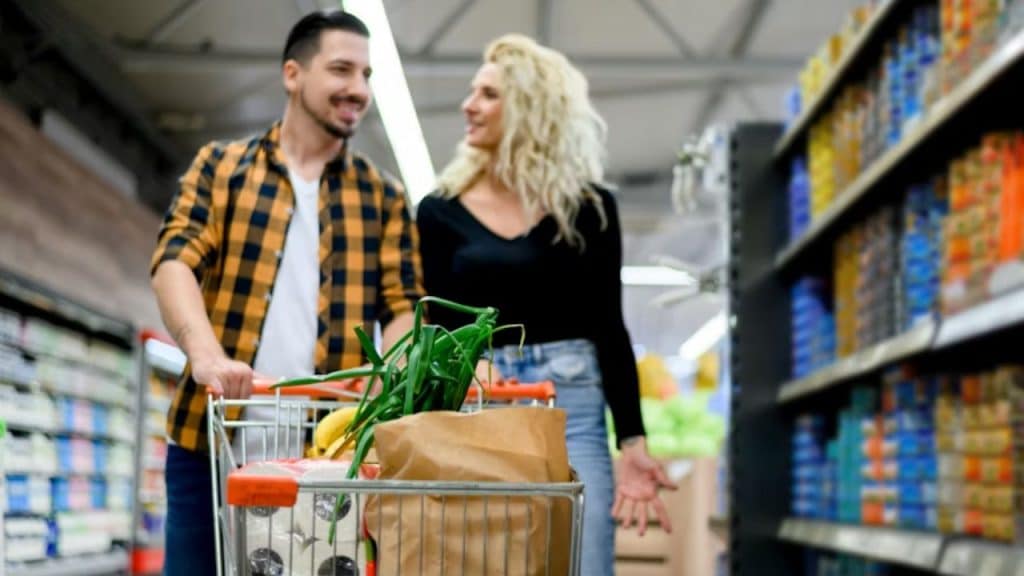 Couple grocery shopping together, woman pointing something out while man listens
