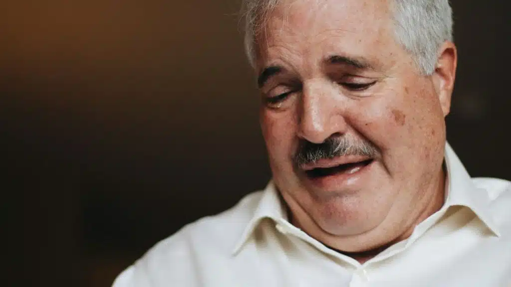 Close-up of an older man with a mustache and a tear in his eye.