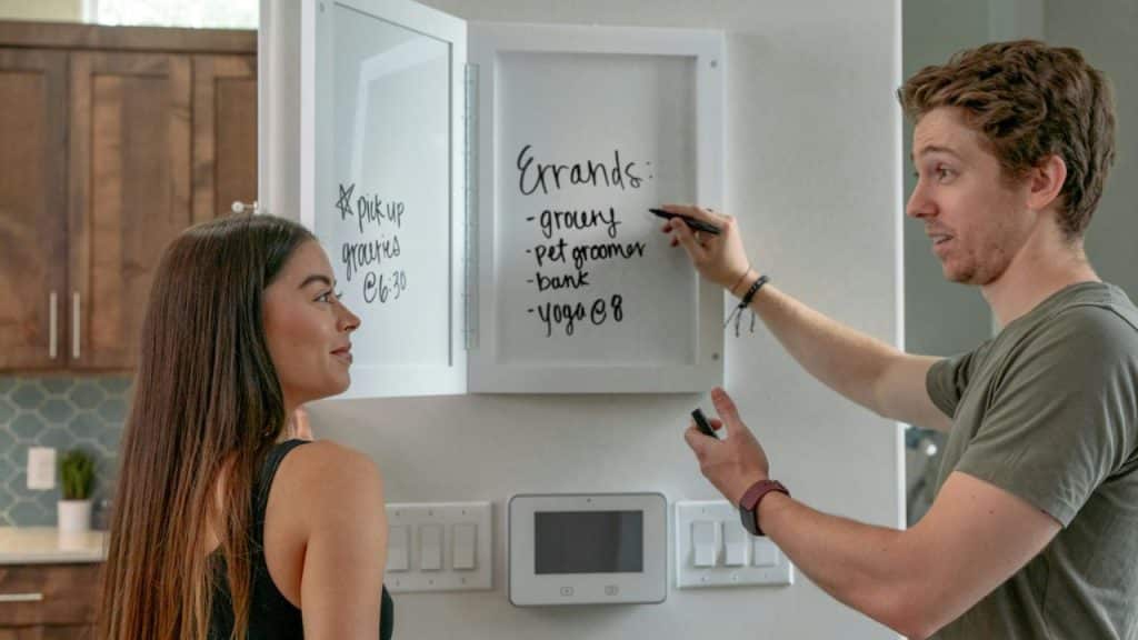 Man and woman looking at a whiteboard with a list of "Errands" on it.