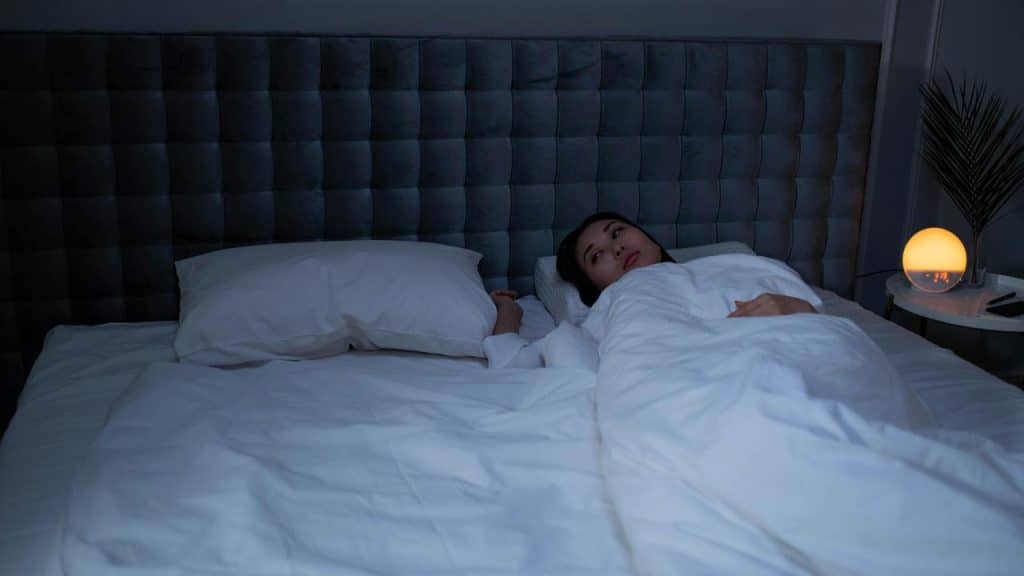 A woman lying awake in bed at night.