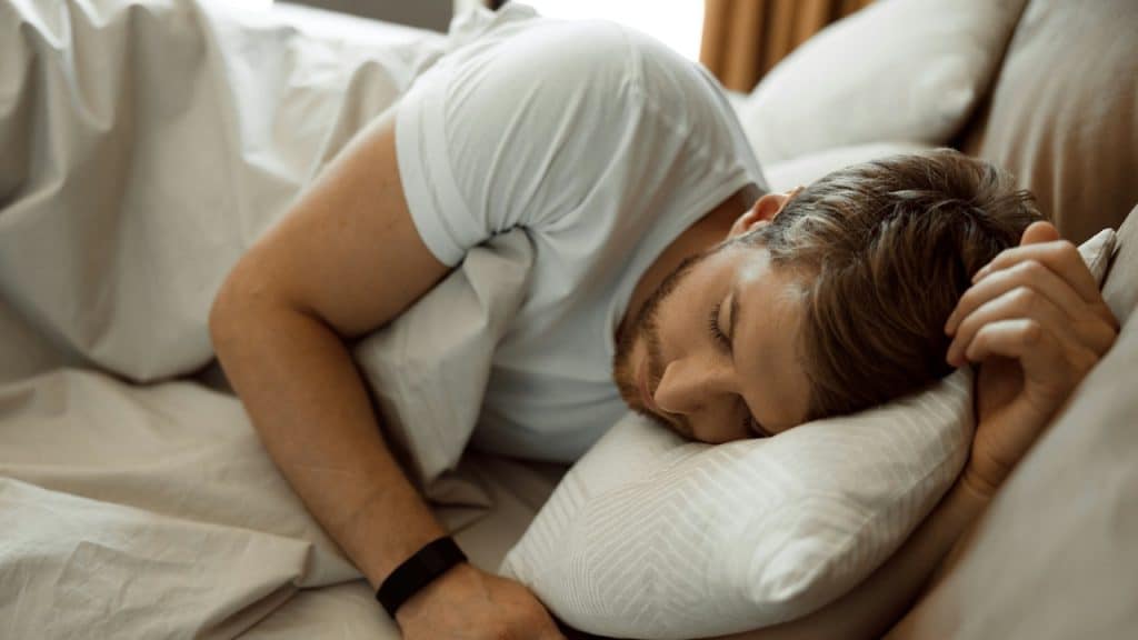 A man in a white t-shirt sleeping peacefully.