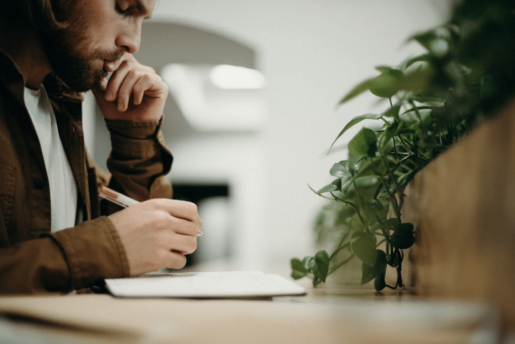 Man Wearing Brown Jacket Using Pen