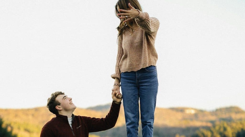 A woman standing while her partner holds her hand.