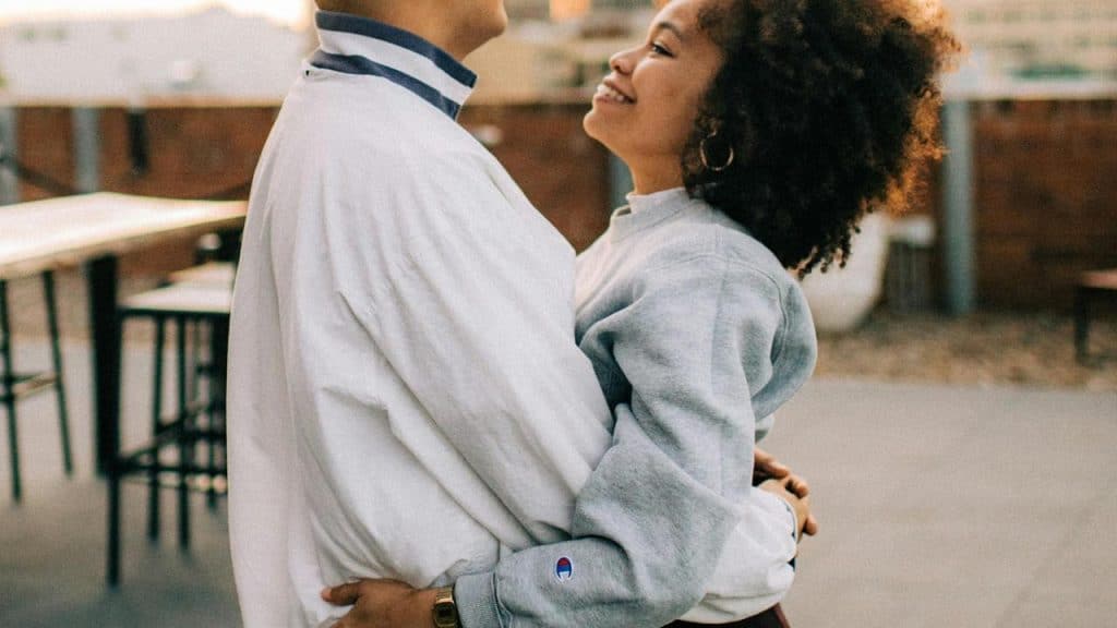 A couple smiling and holding each other outdoors.