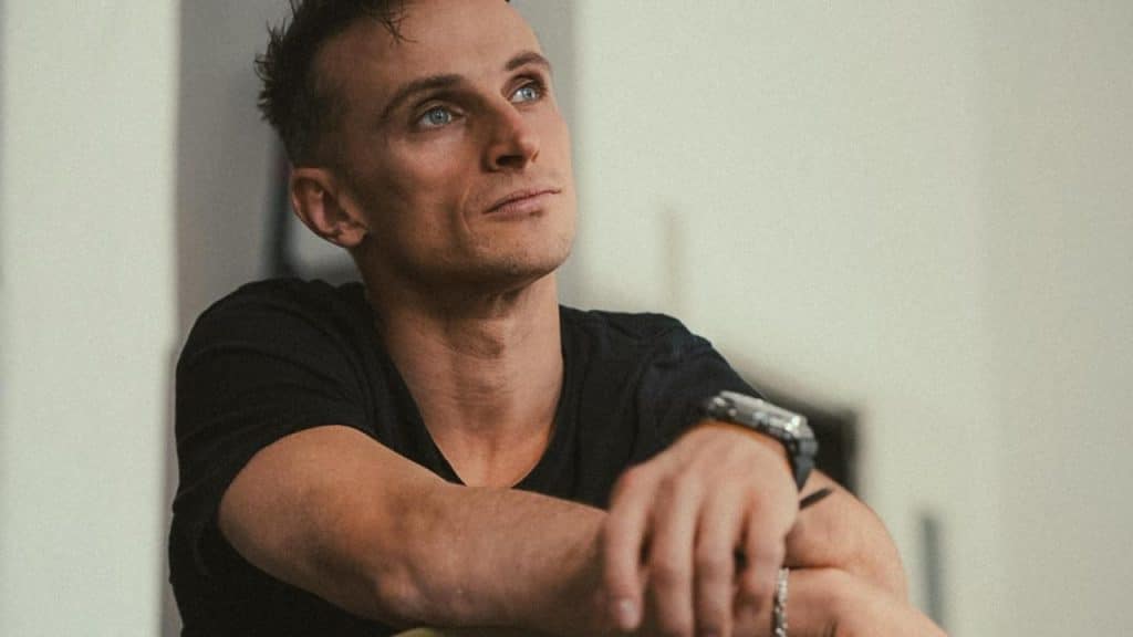 A man sitting with his arms on his knees looking upward thoughtfully.