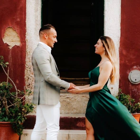 A man and a woman standing in front of a red building.