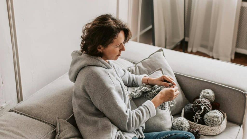 A woman sitting on a couch knitting.