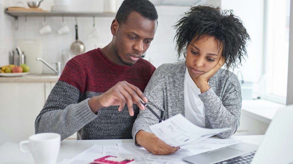 An angry man showing monthly bills to his wife.