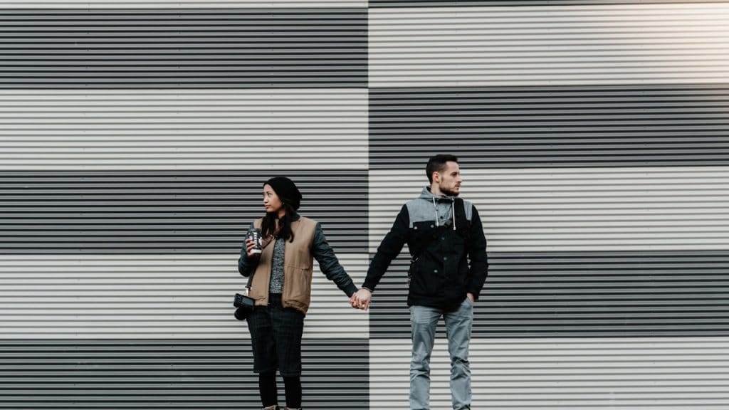 A couple holding hands but looking away from each other.