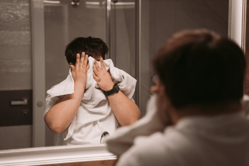 Man in White Shirt Using Towel to Wipe the Face