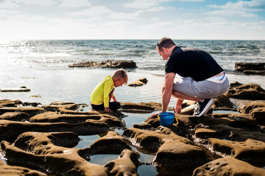 The man is playing with his son on the beach.