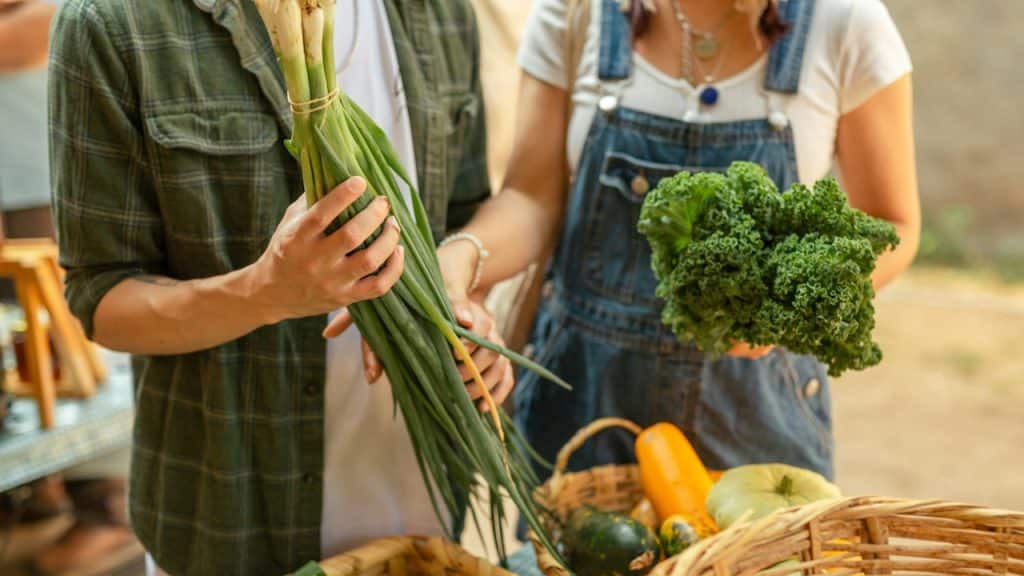 A couple standing next to a vegetable market.