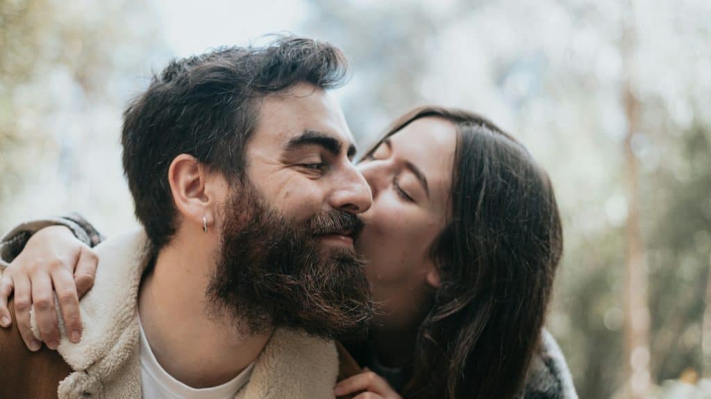 A woman kissing her man outdoors.