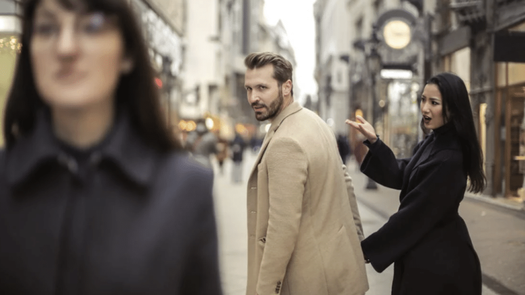 A man looking at another woman while with his wife