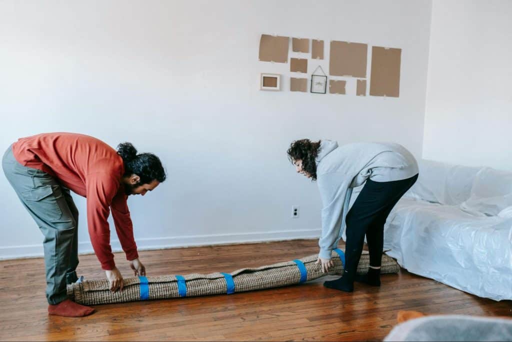 A man and woman lifting carpet