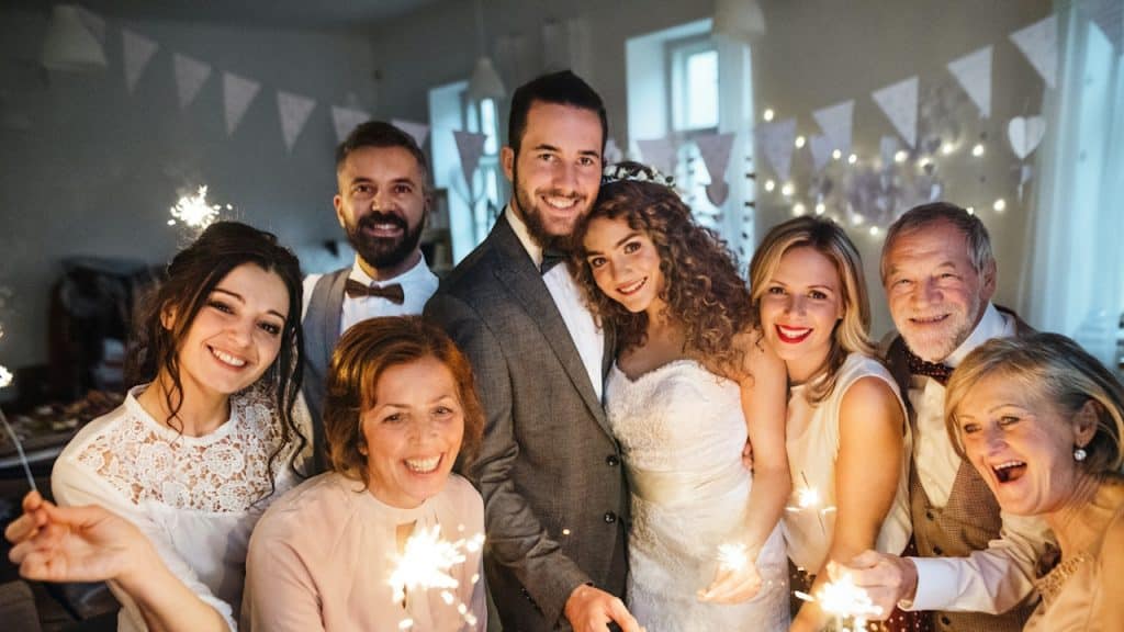 Bride and groom posing for wedding photo with family.