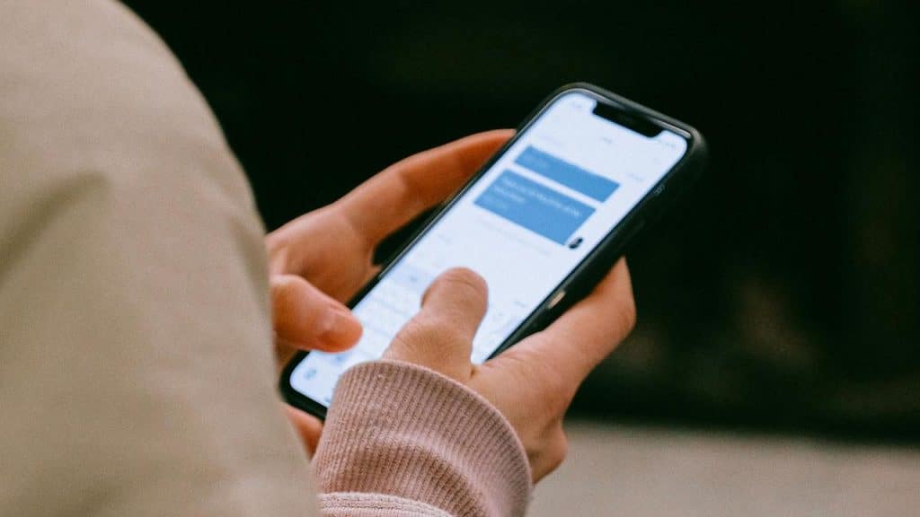 A person holding a smartphone and typing a message.