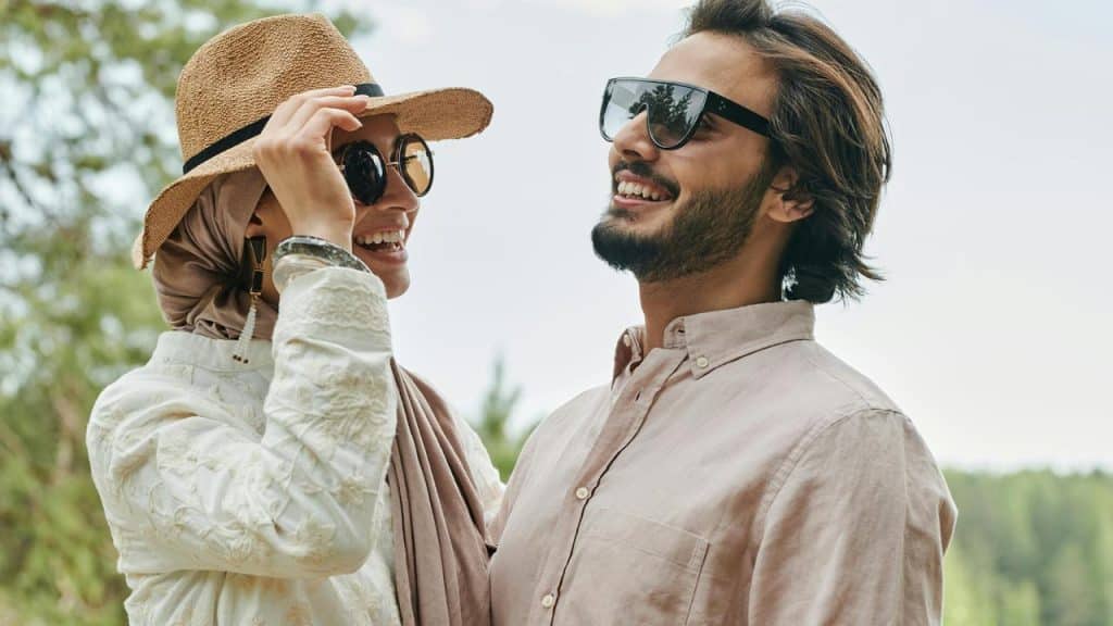 A smiling couple wearing sunglasses and enjoying time outdoors.