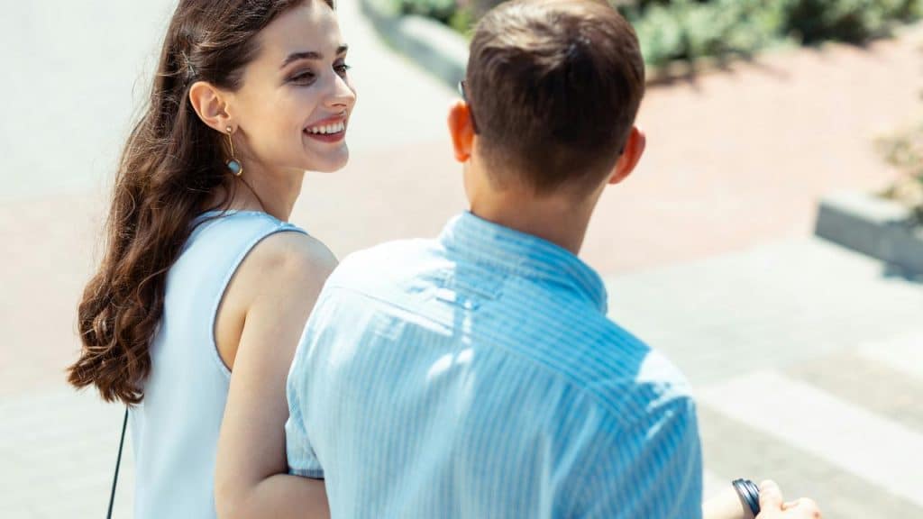 A smiling woman walking outdoors with a man.