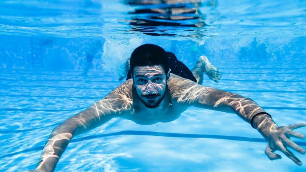A handsome man swimming underwater.