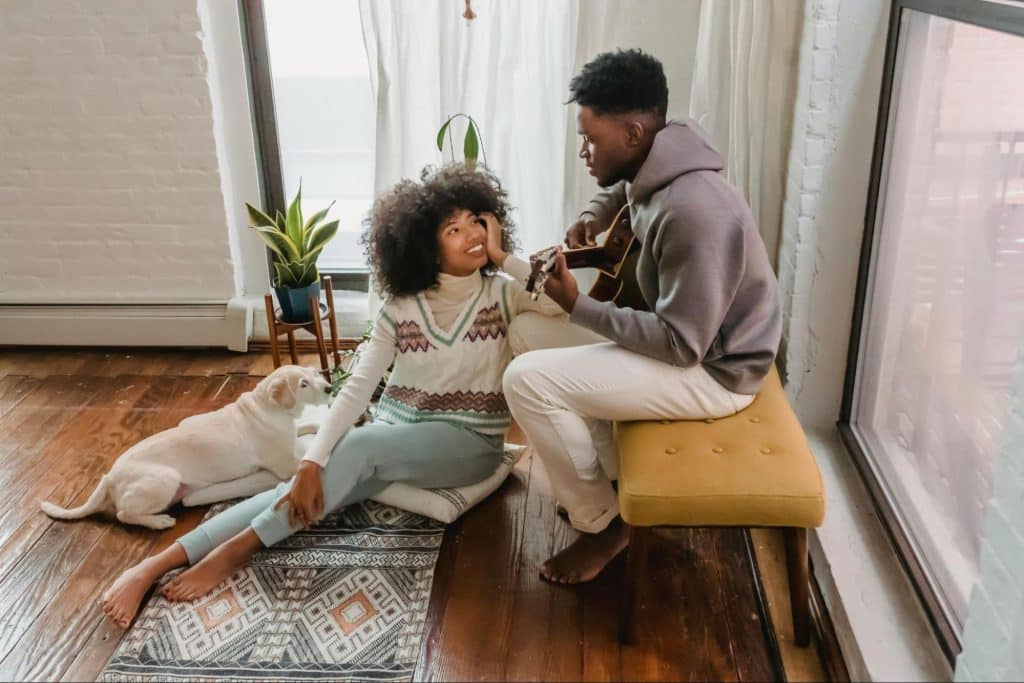 A man playing a guitar and a woman listening to music