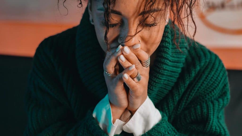 A woman with her hands clasped to her face looking emotional.