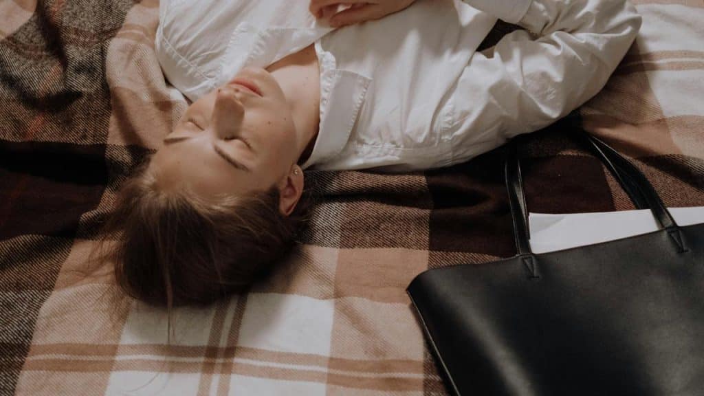 A woman lying on a plaid blanket with her eyes closed.