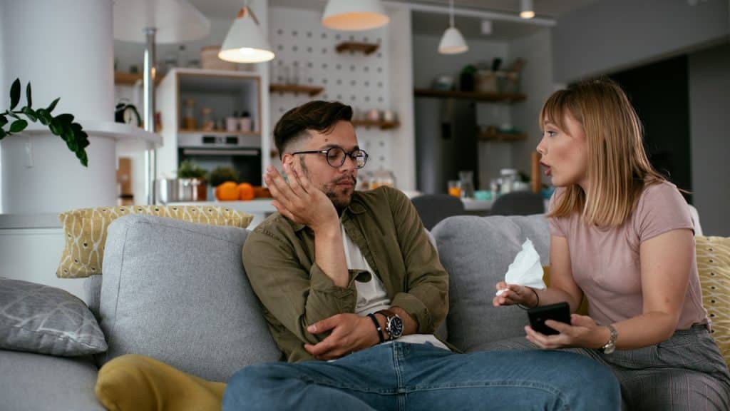 A man and a woman arguing while sitting on a couch.