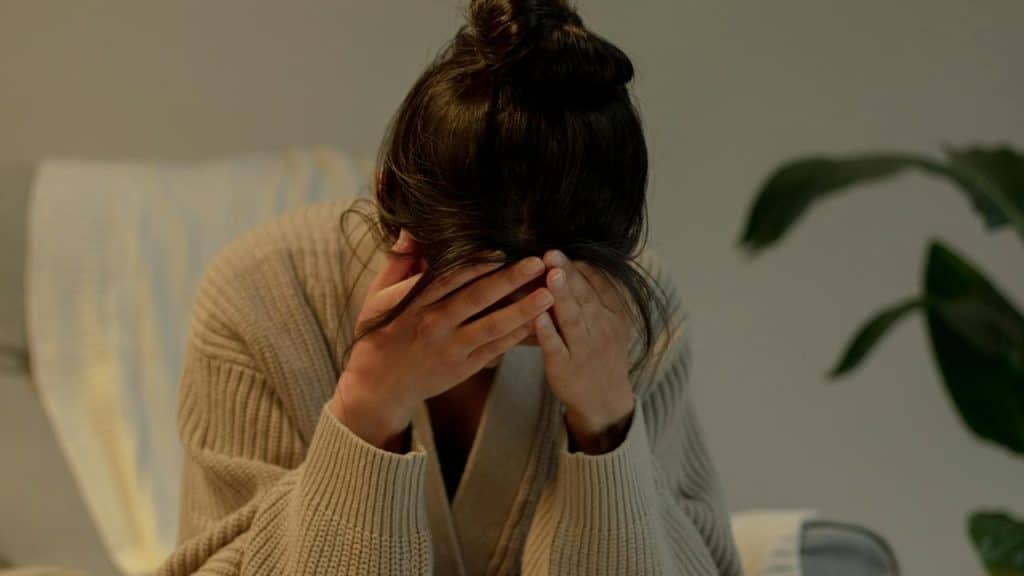 A person sitting with their face in their hands.