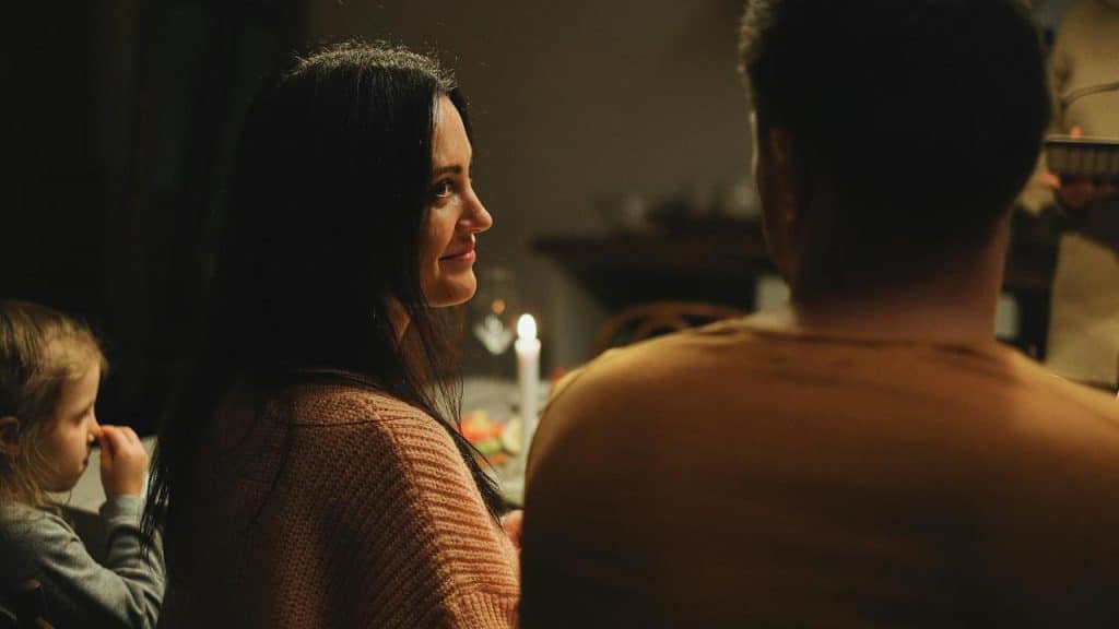 A woman smiling at a man during a cozy candlelit dinner with family.