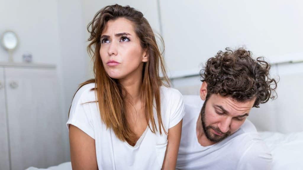 A distressed woman looks upward while a man's curly head is visible looking down next to her.