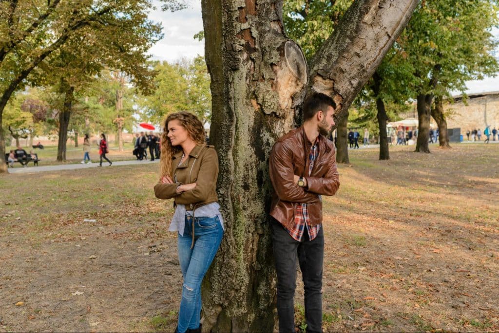 A man and woman leaning on a tree