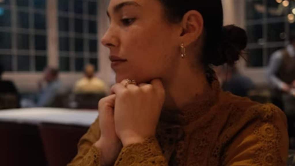 Woman sitting at dinner with arms folded, looking frustrated