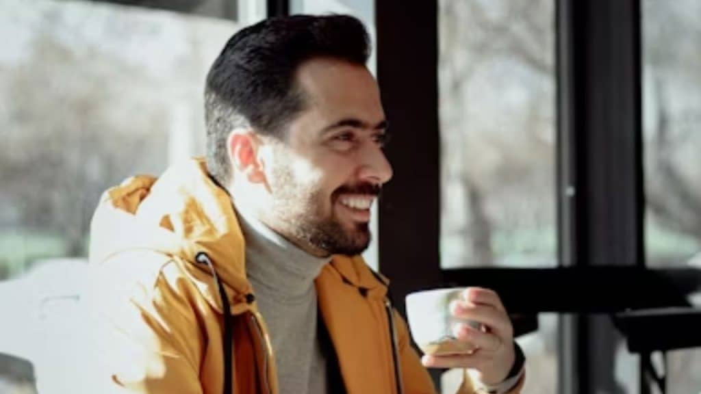 A man smiling confidently while sitting alone at a café.