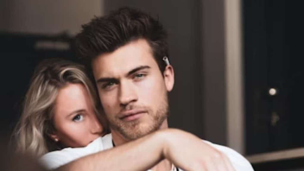 A man looking away while his partner leans on his shoulder.