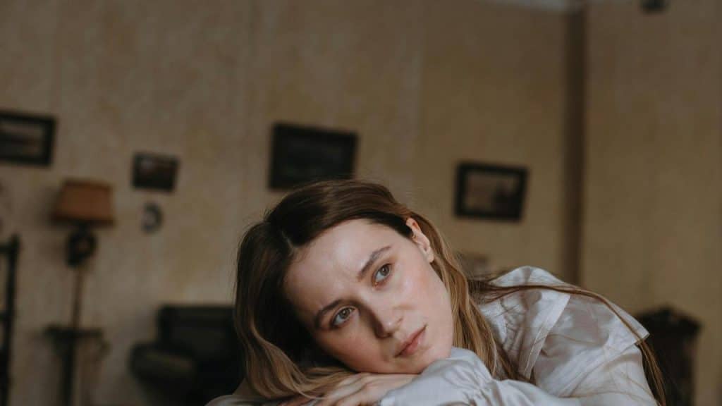 A woman resting her head on her arms looking thoughtful.
