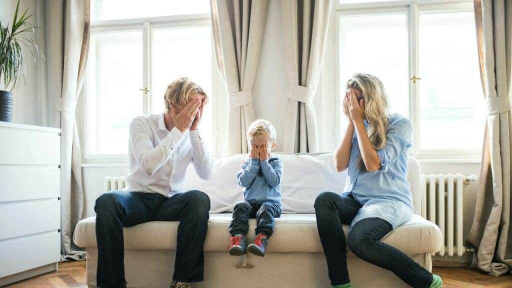 A couple playing peekaboo with their toddler boy.