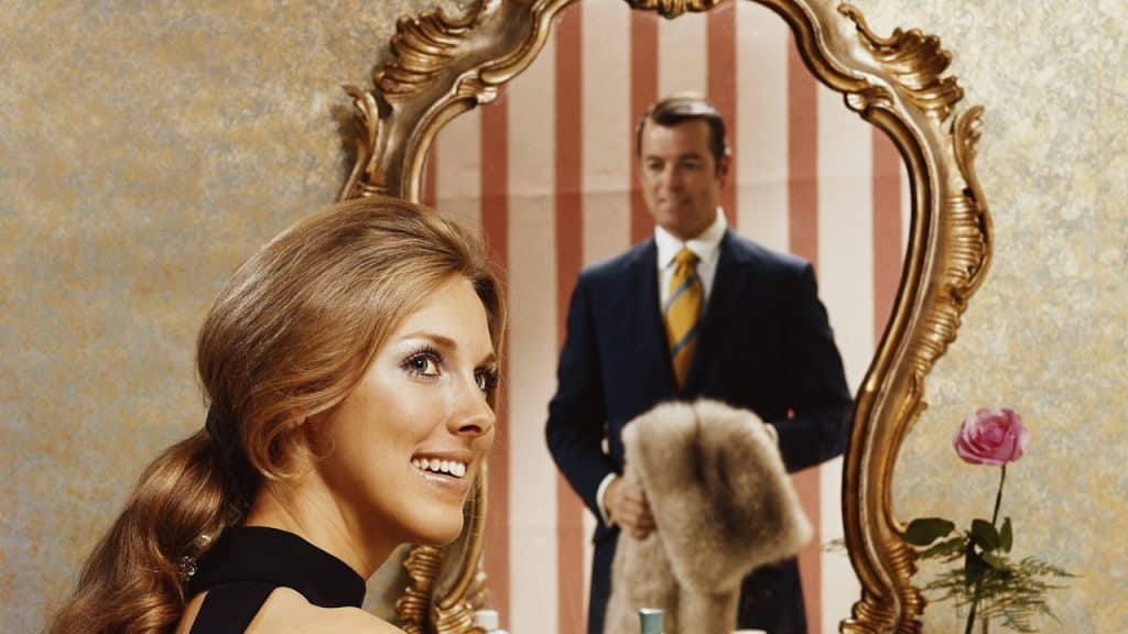 A woman sitting in a chair in front of a mirror.