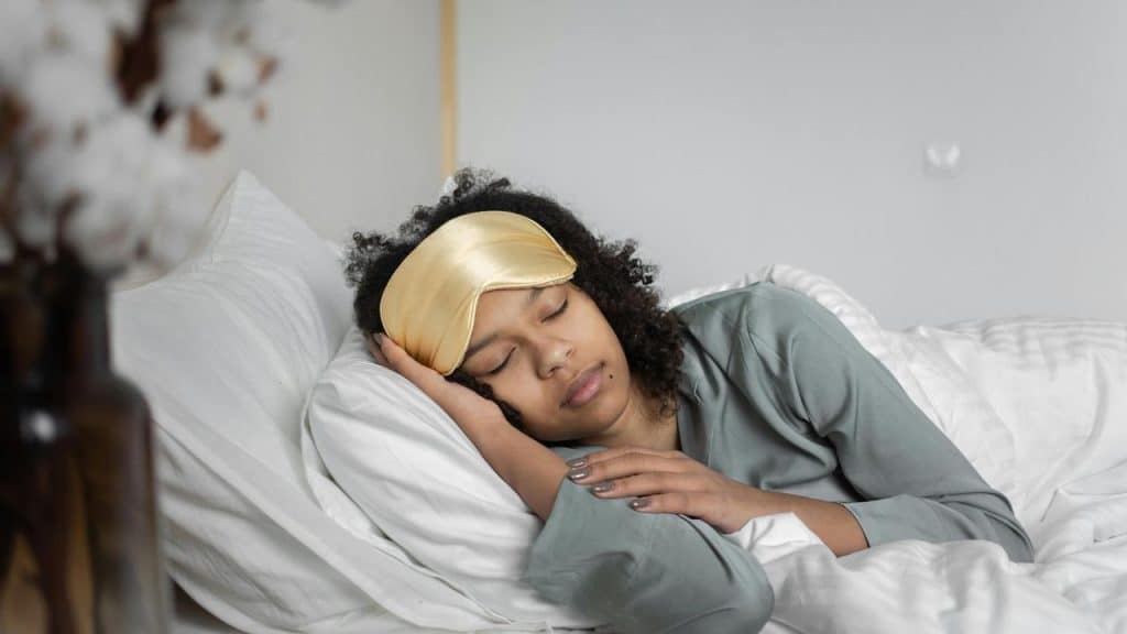 A woman sleeping in bed with a satin sleep mask.