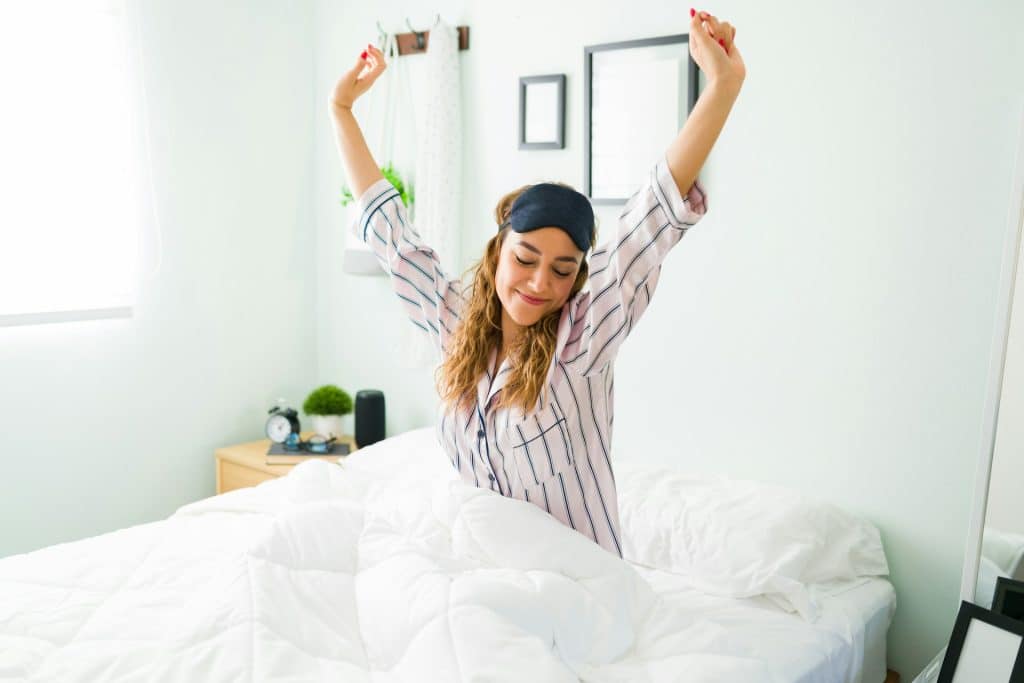 The woman is stretching her arms after waking up.