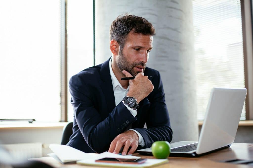 The businessman is using his laptop in his office.