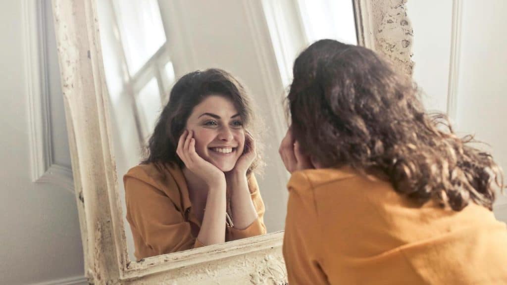 A person smiling at their reflection in a mirror.