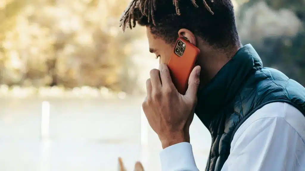 A person holding a phone to their ear while standing outdoors.